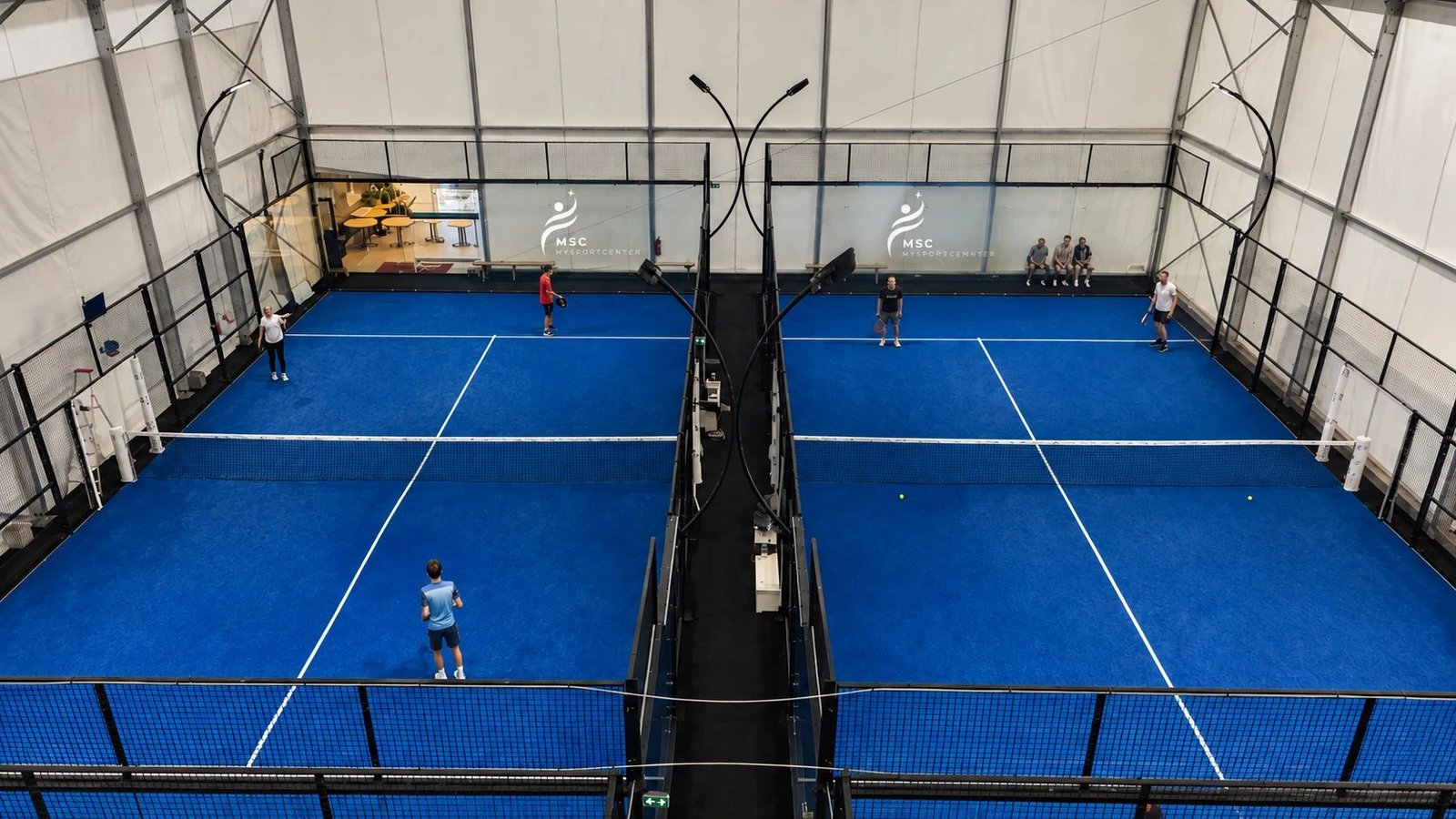 Vue en hauteur des deux terrains de padel indoor My Sport Center, joueurs en pleine partie